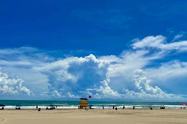 Gulf of Mexico beach on South Padre Island with big blue sky, dramatic clouds, and a lifeguard stand on the sand